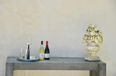 a table with two bottles of wine and a vase at maison bertuli Oliviers Aircon, heated saltwater Pool, 2 Bedrooms in Oppède