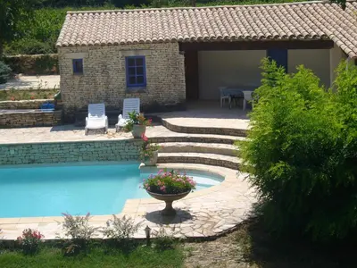 a swimming pool with a patio and a house at Goult (LUBERON) A 150 m de la piste cyclable Maison en campagne avec Gde piscine in Goult