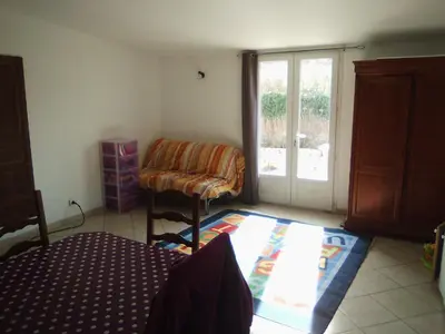 a living room with a chair and a sliding glass door at Goult (LUBERON) A 150 m de la piste cyclable Maison en campagne avec Gde piscine in Goult