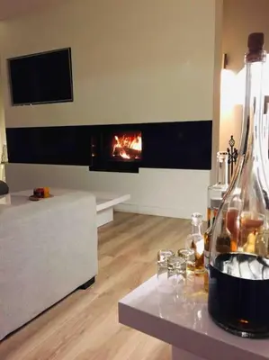 a living room with a fireplace and a bottle of wine at villa entre st rémy de provence et avignon in Noves