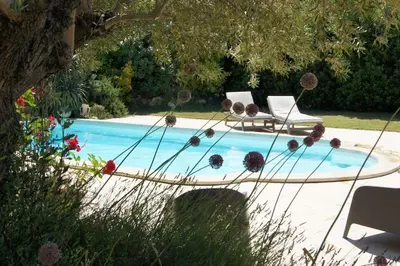 a swimming pool with a table and a chair next to it at villa entre st rémy de provence et avignon in Noves