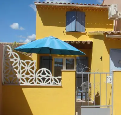 a yellow building with a blue umbrella on a balcony at vacances en provence cyprès in Mormoiron