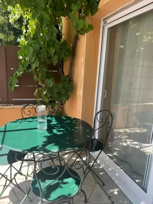 a green glass table and chairs on a patio at Le Pavillon de Nina in Puget