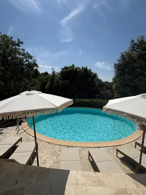 a swimming pool with an umbrella and two chairs at Le Pavillon de Nina in Puget