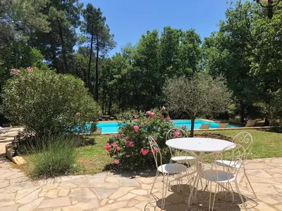 a table and chairs in front of a swimming pool at Le Clos des Cigales in Roussillon