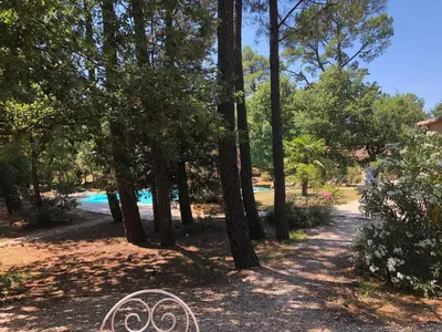 a path in a park with trees and a swimming pool at Le Clos des Cigales in Roussillon