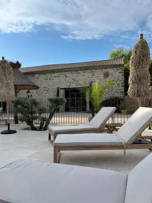 a patio with two lounge chairs and a building at LE MAS MILA in Monteux
