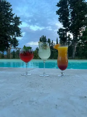 three wine glasses sitting on a table next to a pool at LE MAS MILA in Monteux