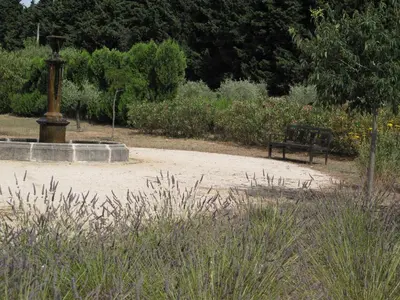 a park with a park bench and a fountain at Mirabelle en Provence in Eygalières