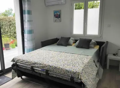 a bed sitting in a room with windows at Charmant Appartement au calme avec piscine au pied du Ventoux en Provence in Carpentras