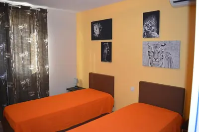 two orange beds in a room with pictures on the wall at Le Cavaou in Mérindol