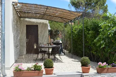 a patio with a table and chairs under a pergola at Le Cavaou in Mérindol