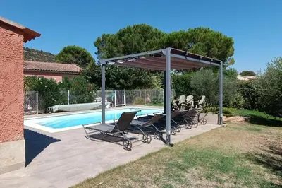a group of chairs under a canopy next to a swimming pool at Le Cavaou in Mérindol