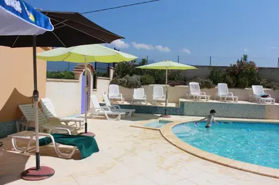 a pool with chairs and umbrellas and a person in the water at vacances en provence olivier in Mormoiron