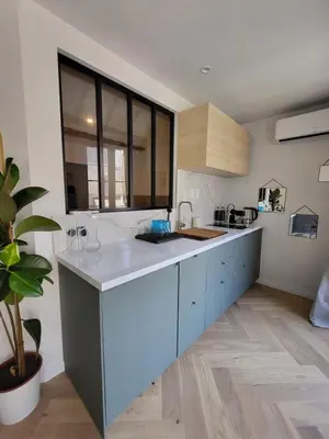 a kitchen with blue cabinets and a large window at Appartement des Augustins in Aix-en-Provence