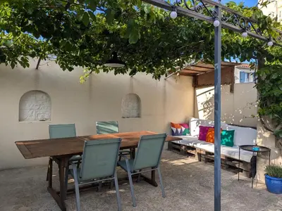 a wooden table and chairs under a tree at Appartement spacieux et charmant in Caumont-sur-Durance