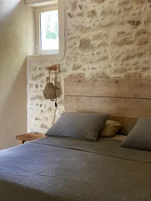 a bedroom with a bed with a stone wall at Eden - Mas de Rousseau in Eyragues