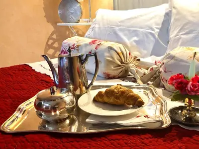 a tray with a plate of food on a bed at L’île aux fleurs in Ventabren