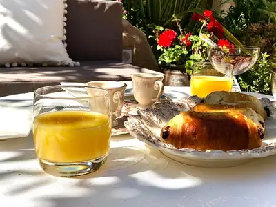 a table with a plate of food and glasses of orange juice at L’île aux fleurs in Ventabren