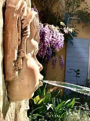 a statue on the side of a building with purple flowers at L’île aux fleurs in Ventabren