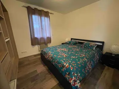 a bedroom with a bed with a green comforter and a window at Logement Le Puy Sainte Réparade in Le Puy-Sainte-Réparade