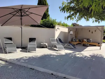 a patio with two chairs and an umbrella at MAS LAURIE in Cheval-Blanc