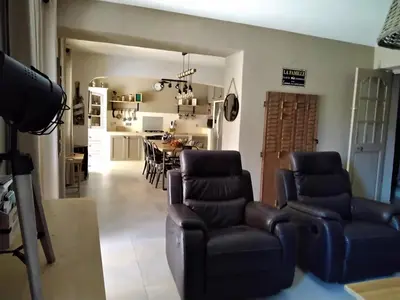 a living room with chairs and a table and a kitchen at MAS LAURIE in Cheval-Blanc