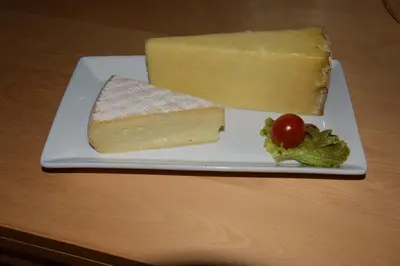 a piece of cheese and a tomato on a plate at Ici et Là - Chambres d'hôtes in Velleron