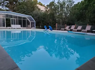 a swimming pool with chairs and blue water at Cécile - Mas de Rousseau in Eyragues