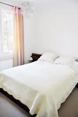a bedroom with a white bed and a chandelier at Lumière de Provence in Mollégès