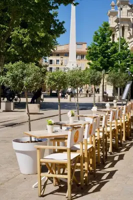 a row of tables and chairs with a monument in the background at Maison en Provence avec piscine in Éguilles