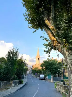 a street with a church and a car on the road at Logement neuf, tout confort, au coeur du village in Saint-Didier