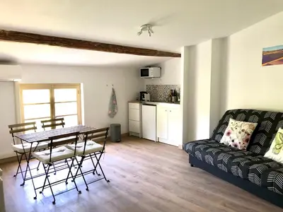 a living room with a table and a couch at Logement neuf et climatisé, au coeur du village in Saint-Didier