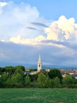 a white church with a steeple on top of a field at Logement neuf et climatisé, au coeur du village in Saint-Didier