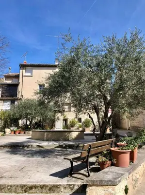 a bench in a courtyard with trees and plants at Logement neuf et climatisé, au coeur du village in Saint-Didier