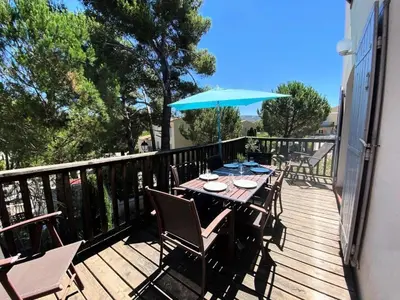 a wooden deck with a table and an umbrella at Les Coteaux de Pont Royal en Provence - maeva Home - Maison chaleureuse climatisée 4 pièces 6 personnes - Prestige - super Home MAE-2304 in Mallemort