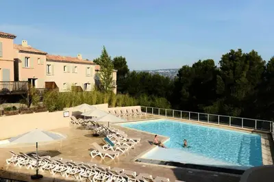 a large swimming pool with chairs and umbrellas at Les Coteaux de Pont Royal en Provence - maeva Home - Maison chaleureuse climatisée 4 pièces 6 personnes - Prestige - super Home MAE-2304 in Mallemort