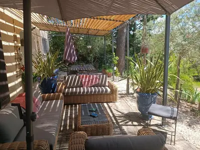 a patio with couches and chairs under an umbrella at Villa provençale et ses grands pins in Pernes-les-Fontaines
