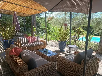 a patio with couches and a table and an umbrella at Villa provençale et ses grands pins in Pernes-les-Fontaines