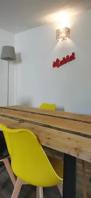 a wooden table with yellow chairs and a light at La Petite Reine Du Ventoux in Sault-de-Vaucluse