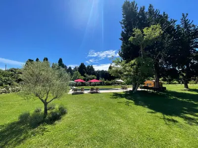a park with benches and red umbrellas in the grass at Mas Etienne Piscine&Nature Saint-Rémy Conciergerie in Saint-Rémy-de-Provence