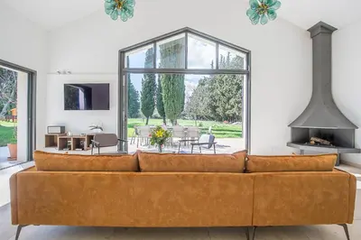 a couch in a living room with a large window at Mas Etienne Piscine&Nature Saint-Rémy Conciergerie in Saint-Rémy-de-Provence