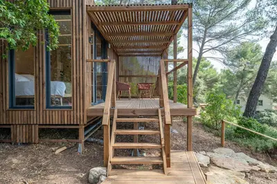 a tree house with a deck and a ladder at Le Chant des Pins Lodge & Spa Tour de Keyrié in La Mignarde