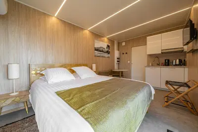 a bedroom with a large bed and a kitchen at Le Chant des Pins Lodge & Spa Tour de Keyrié in La Mignarde