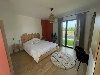 a bedroom with a bed and a large window at Noyau & Pepin in Rognes