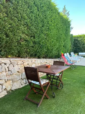 a wooden table and chairs sitting on the grass at T2 avec jardin et piscine privée in Velaux
