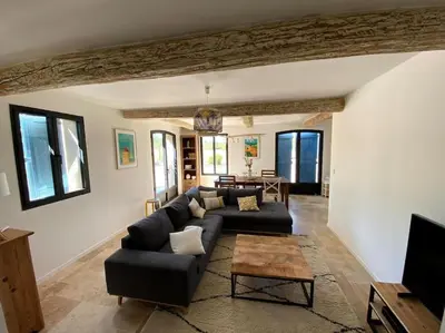 a living room with a black couch and a table at Mas de charme avec piscine au coeur des Alpilles in Eygalières