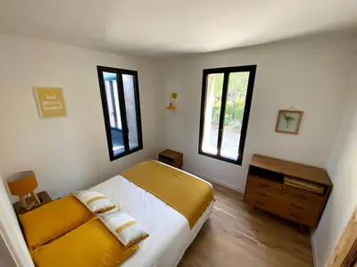 a bedroom with a bed and two windows at Mas de charme avec piscine au coeur des Alpilles in Eygalières