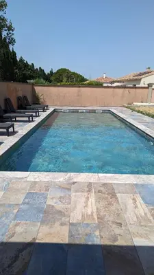 a swimming pool with benches on the side of a building at Spa NESSA in Saint-Andiol