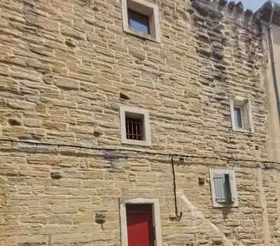 a brick building with a red door and windows at Petit appart entier au cœur des REMPARTS - Netfix et connection fibre gratuits in Carpentras